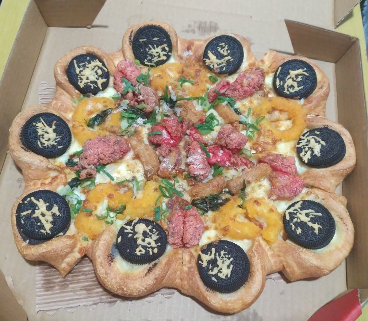 Crean pizza "infernal": Tiene galletas Oreo, pollo frito y trozos de calamar